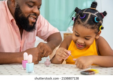 Happy family African father applying nail polish to little daughter in living room. Dad and child girl kid enjoy and having fun leisure activity spending time together with beauty treatment at home - Powered by Shutterstock