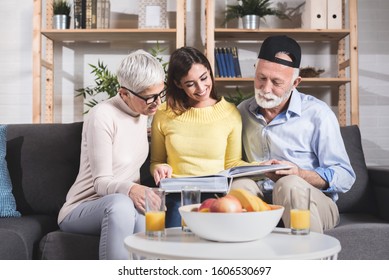 Happy Family After A Sunday Lunch Looks At An Old Picture Photo Album. Memories Concept