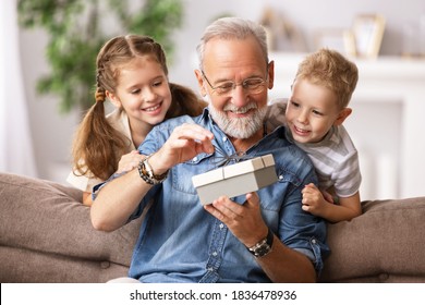 Happy family aged grandfather and grandchildren girl   and boy opening gift box while resting on sofa during holiday celebration at home
 - Powered by Shutterstock