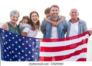 Happy family with an american flag at the beach - Powered by Shutterstock