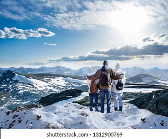 Happy Family With Arms Around Each Other Enjoying Beautiful  Snowy Mountain View.  Friends On Winter  Hiking Trip. View From Trail Ridge Road, Rocky Mountain National Park, Colorado, USA