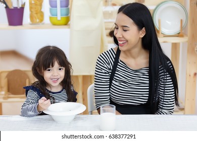 Happy Family, Asian Child Eat Cereal And Milk For Breakfast With Her Mother.