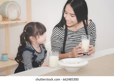 Happy Family Of Asian Mom Is Drinking Milk With Her Cute Daughter In The Morning. Photo Series Of Family, Kids And Happy People Concept.