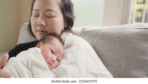 Happy family Asian mother holding caressing hugging newborn baby infant, mom hand being burped and patted rubbed on the back of the child to encourage burping after eating full milk, parenthood, love	