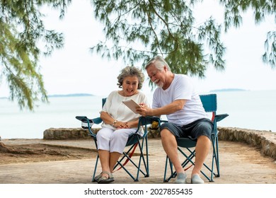 Happy Family Asian Senior Couple Using Tablet Computer With Internet Video Call With Their Family Or Friend On The Beach In Summer Day. Healthy Retired Man And Woman Enjoy With Summer Holiday Vacation