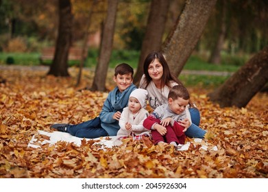 Happy Family At Autumn Leaves Park. Mother With Three Kids.