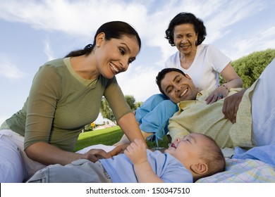 Happy family with baby boy relaxing in park