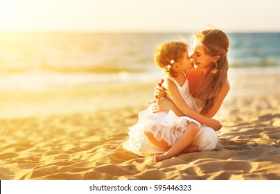 Happy Family At The Beach. Mother Hugging Baby Daughter At Sunset
