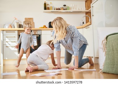 Happy family. Beautiful blond woman and her adorable children drawing and playing on the floor - Shutterstock ID 1413597278