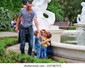 Happy family, beautiful mother cuddling with her small children near a fountain in central park Cluj-Napoca on May 19, 2018.
