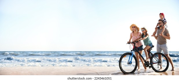 Happy family with bicycle on sandy beach near sea, space for text. Banner design - Shutterstock ID 2243461051