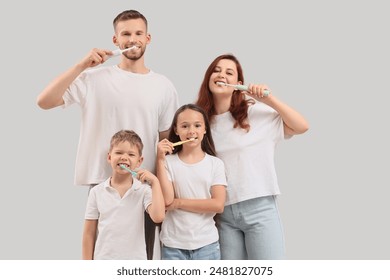 Happy family brushing teeth on light background - Powered by Shutterstock