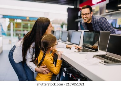 Happy family buying laptop in store.