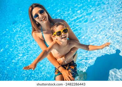 Happy family of a caucasian mother and boy having fun together inside a swimming pool in summer - Powered by Shutterstock