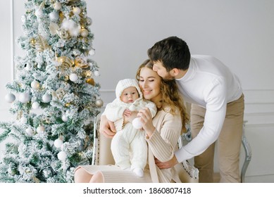 Happy Family Celebrates Christmas And New Year At Home In The Living Room Near The Christmas Tree. Family Portrait Of Dad, Mom And Baby