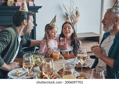 Happy family celebrating birthday of little girl while sitting at the dining table at home - Powered by Shutterstock