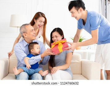 Happy Family Celebrating And Giving Gift To Father