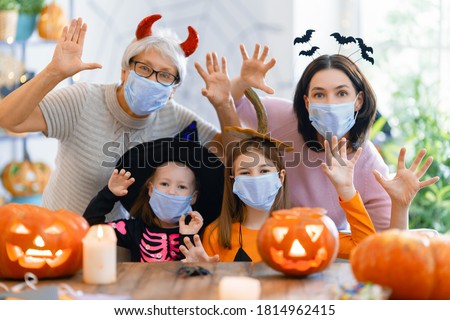 Happy family celebrating Halloween. Grandmother, mother and children wearing face masks protecting from COVID-19.