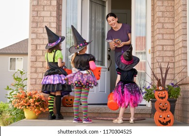 Happy family celebrating Halloween! Young mom treats children with candy. Funny kids in carnival costumes. - Shutterstock ID 1170304525
