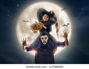 Happy Family Celebrating For Halloween! Young Dad And His Kid In Carnival Costumes On Night Sky Background.