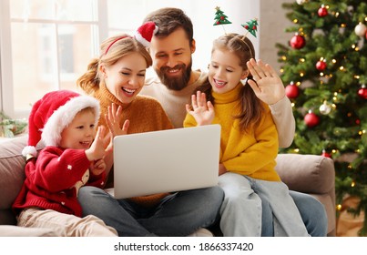 Happy Family Cheerful Parents And Joyful Children Make A Video Call To Relatives On  Holiday Near The Christmas Tree At Home
