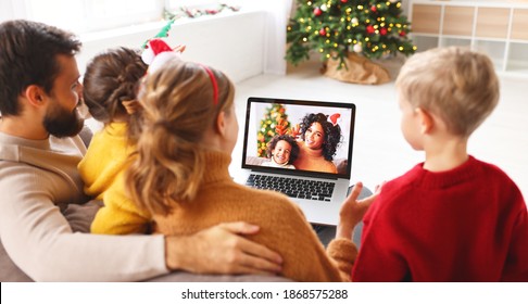 Happy Family Cheerful Parents And Joyful Children Make A Video Call To Friends On  Holiday Near The Christmas Tree At Home
