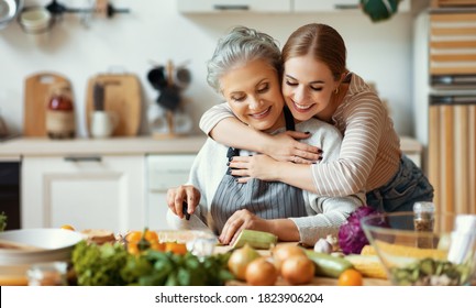 Happy Family Cheerful Young Woman Embracing Mature Mother While Preparing Healthy Dish With Fresh Vegetables In Home Kitchen
