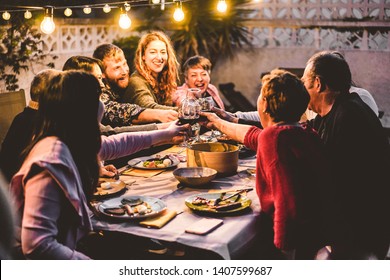Happy family cheering with red wine at barbecue dinner outdoor - Different age of people having fun at weekend meal - Food, taste and summer concept - Focus on hands toasting