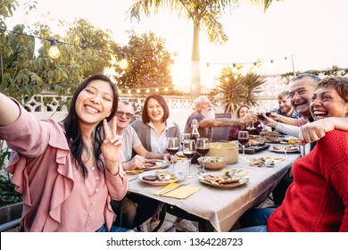 Happy family cheering and toasting with red wine glasses at dinner outdoor - People with different ages and ethnicity  having fun at bbq party - food and drink, retired and young people concept