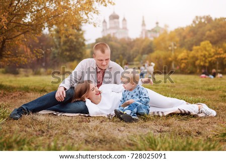 Happy family with child in autumn park sitting on a plaid