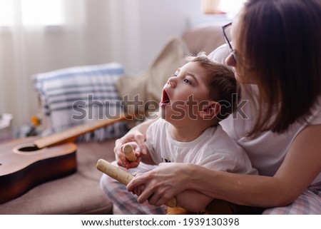 Happy family with a child with cerebral palsy. The mother and her disabled son lead a normal life. Leisure time together. Child development games at home. Wooden musical instruments. Rehabilitation 