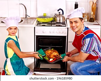 Happy Family With Child Cooking Chicken At Kitchen.