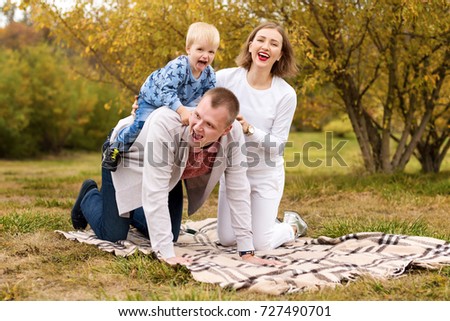 Happy family with child having fun in autumn park sitting on a plaid.