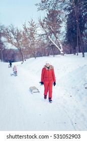 Happy Family With Child On Sled Walking In Winter Outdoors