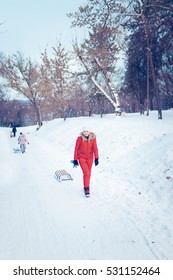 Happy Family With Child On Sled Walking In Winter Outdoors