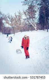 Happy Family With Child On Sled Walking In Winter Outdoors