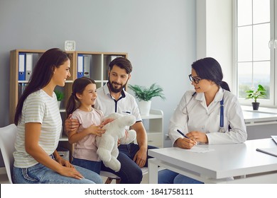 Happy family with child in pediatrician's office consulting friendly young female doctor. Mother, father and daughter talking to supportive paediatrician during regular check-up in modern hospital