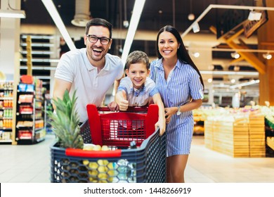 Happy family with child and shopping cart buying food at grocery store or supermarket - Powered by Shutterstock