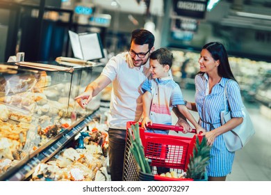 Happy Family With Child And Shopping Cart Buying Food At Grocery Store Or Supermarket