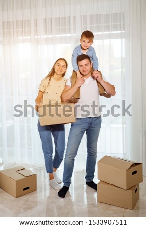 happy family and child son against the background of panoramic windows. Woman holding cardboard box
