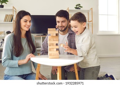 Happy Family With Child Taking Blocks From Tumble Tower. Smiling Young Caucasian Couple With Little Son Enjoying Free Time On Weekend At Home, Having Fun And Playing Exciting Board Game Together