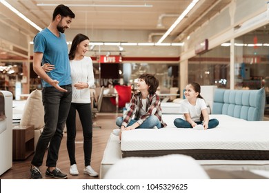 Happy family with children came in furniture store to buy mattress. Young couple with happy children in orthopedic mattress store.