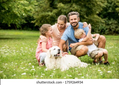 Happy Family With Children And Dog Together In The Garden In Summer