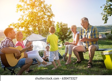 Happy Family And Children Enjoying With Guitar In A Tent
