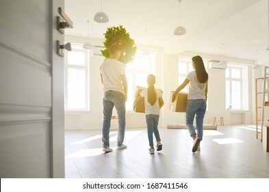 Happy family with children moving with boxes in a new apartment house. Back view.