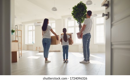 Happy family with children moving with boxes in a new apartment house. Back view. - Shutterstock ID 1724096326