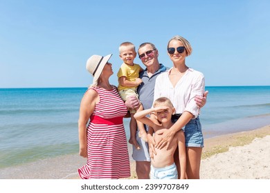 Happy family with children on the seashore. Grandparents, grandchildren and their mother hug and laugh on a bright sunny day. Love and tenderness. - Powered by Shutterstock