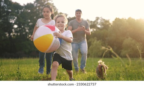 happy family. children and parents run in the park play ball. happy family kid concept. boy runs on grass in park holding the ball. group of children and parents family play in park run dream - Powered by Shutterstock