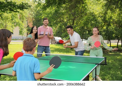 Happy family with children playing ping pong in park