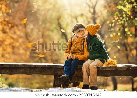 Happy family children sit on the wooden bridge over the water in autumn time.